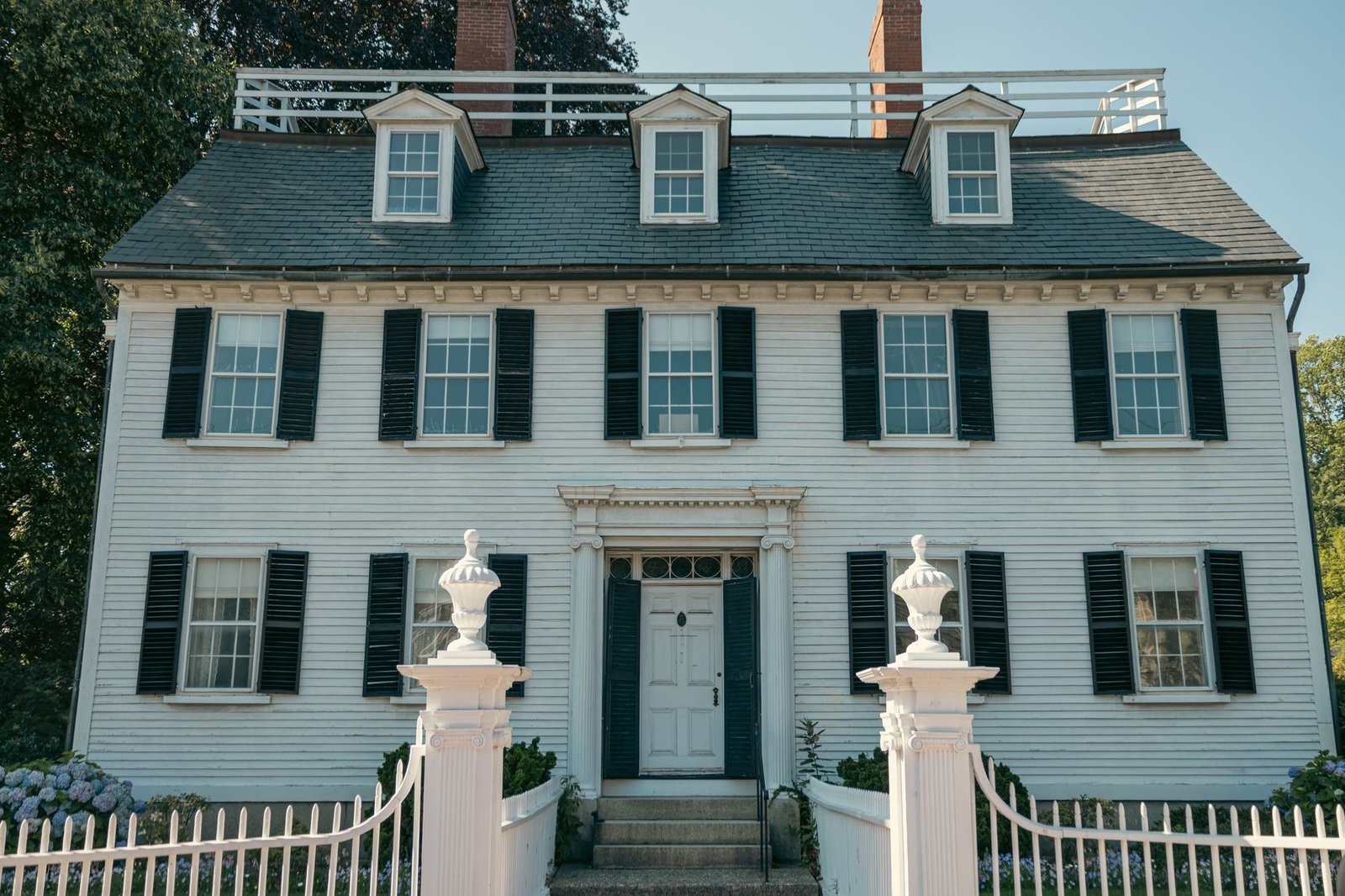 Colonial-style New England home with a white picket fence
